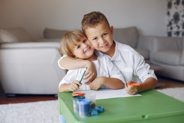 Brother and sister in a playing room. Children drawing at the table