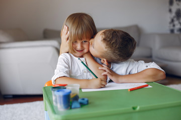 Brother and sister in a playing room. Children drawing at the table