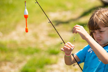 Young girl untangling a knotted fishing line