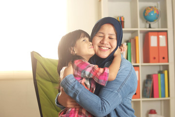 Muslim mother playing with her baby girl, mom and daughter love each other, happy single parent