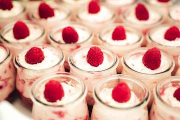 Rows of glasses with raspberry sweet dessert on festive table closeup. Celebration, party, birthday or wedding concept.
