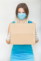 Delivery during coronavirus outbreak. Copy space. Woman hold cardboard box in medical rubber gloves and mask on white background