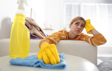 Lazy young woman wiping table at home. Cleaning and housework