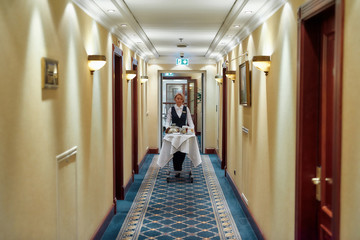 Discover Comfort and Hospitality. Full-length shot of waitress walking along the hall while...