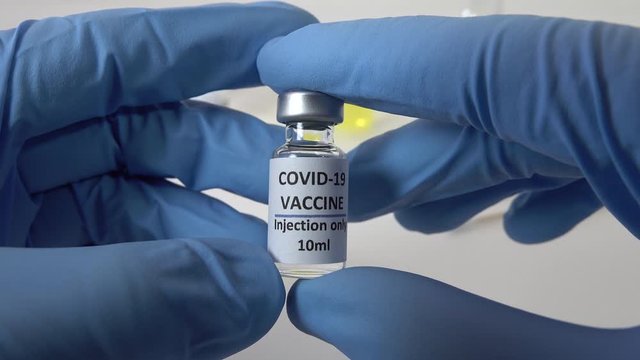 Close-up of medical researcher holding trial vaccine bottle for coronavirus Covid-19
