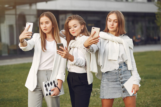 Students in a park. Girls on a campus. Friends with a phone.