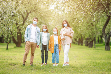 Fototapeta premium Adorable family in blooming cherry garden in masks