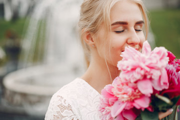 Beautiful girl in a white dress. Woman in a summer park. Lady with a red flowers