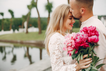 Cute couple in a park. Lady in a white dress. Guy in a white shirt.