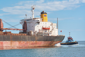Back part of container ship and little ship to the right