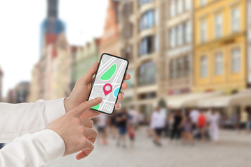 Man searching location with smartphone in city, closeup. Space for text