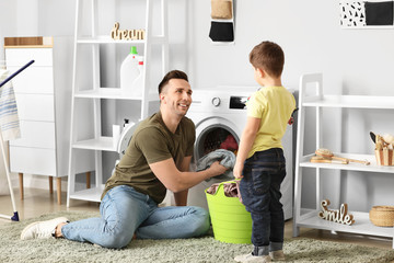 Man and his little son doing laundry at home