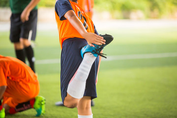 Soccer player is stretching their hands to catch their feet. Warming up the body and foot before the competition or practicing.