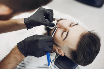 Man with a beard. Hairdresser with a client. Brunette in a barbershop