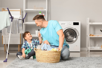 Man and his little son doing laundry at home