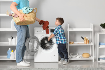 Man and his little son doing laundry at home