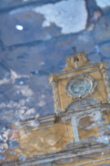 Reflection of a clock arch in a puddle on antigua guatemala streets