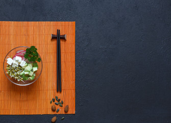 Appetizer of vegetable slices and mung bean sprouts with chopsticks, on a black background, top view with space