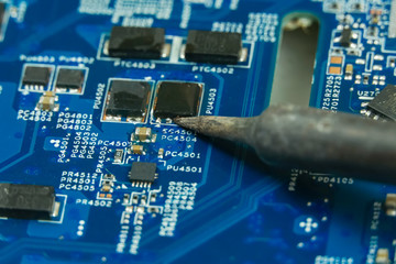 master repairs the motherboard using a soldering iron close up
