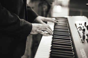 Fototapeta na wymiar Black and white photo of man's hand playing on electronic keyboards. Shallow depth of field. Music, entertainment, wedding, celebration concept.