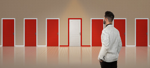 Young man standing in front of many doors. Choice concept