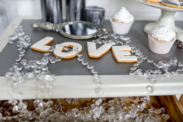 Wedding decorations on the table. Cupcakes with white cream and gingerbread in the form of the word love. Morning of the bride.