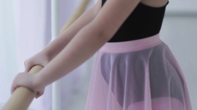 Close up of little ballerina take ballet barre