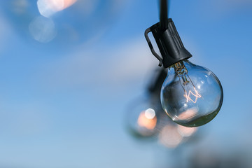 Edison light bulb against a blue sky with lots of out of focus area