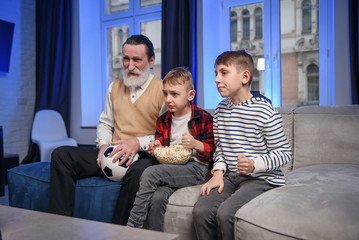 Grandfather and grandson watching television. Grandfather and grandson enjoying at home.