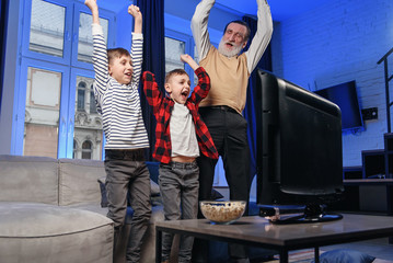 Grandfather and grandson watching television. Grandfather and grandson enjoying at home.