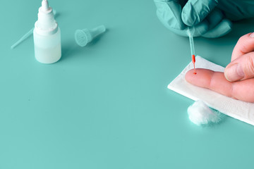 Express COVID-19 test for IgM and IgG antibodies to novel coronavirus SARS-CoV-2, Covid-19. Nurse hand in nitril glove collects patient blood with disposable pipette. Gren mint turquoise background.