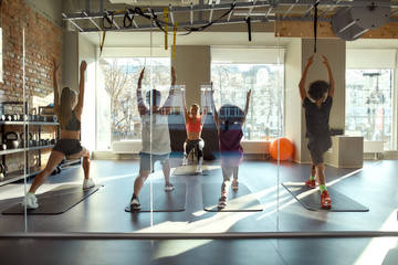 Join the world of yoga. Full-length shot of kids doing yoga exercises together with female trainer in gym. Stretching on a sunny day. Sport, healthy life, physical education concept