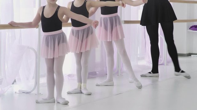 Small ballerinas are repeating the movements with the teacher. ballet lesson in the studio
