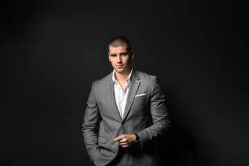 Handsome young man in elegant suit on dark background