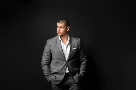 Handsome young man in elegant suit on dark background