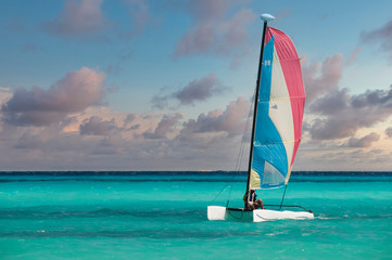 A man sails near the beach in a Hobie-Cat in the turquoise waters of the Mexican Caribbean at...