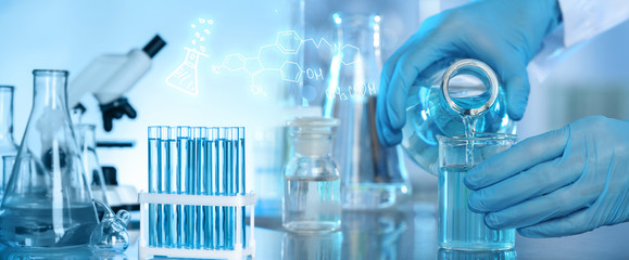 Scientist pouring blue liquid into beaker from Erlenmeyer flask for analysis in laboratory,...