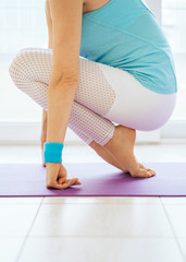 Adult woman's body in sportswear doing yoga at home. Female stand on toes; wellness concept, side view