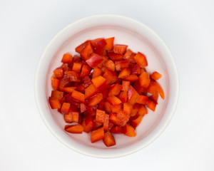 chopped fresh red pepper in a white porcelain bowl on a white background