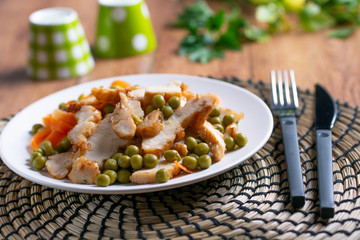roasted chicken meat with pea and carrot garnish - closeup