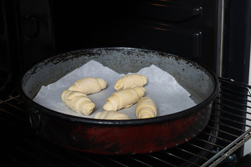 Unbaked rolls in a casserole and ready for backing in the oven. The process of preparing homemade rolls pastry. Domestic and hand made food preparation concept. Close up, selective focus