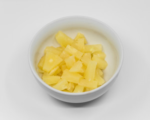 chopped canned pineapple in a white porcelain bowl on a white background