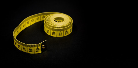 Yellow measuring tape with scale in centimeters. Yellow measuring tape isolated on black background.