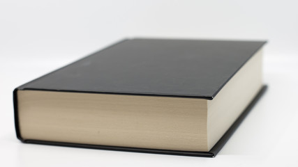 Thick book in hard black cover, yellowed pages. the book lies flat on a white isolated background