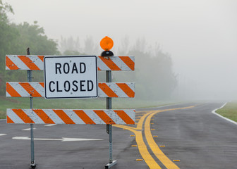 Street closure sign in front of foggy road