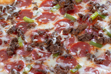 Homemade pizza fresh from the oven and unsliced.  Topped with pepperoni, cheese, peppers, onions, and beef.