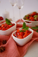 Strawberry dessert in small white tins.  Strawberry dessert decorated with fresh mint.  Bowls with dessert with strawberries on a pink napkin.