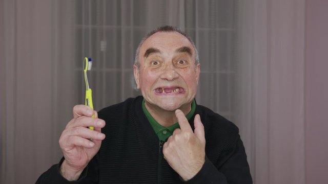 Toothless elderly man with a toothbrush. Closeup.