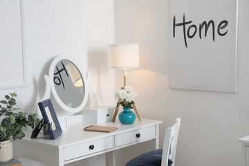 Stylish dressing table with glowing lamp at home