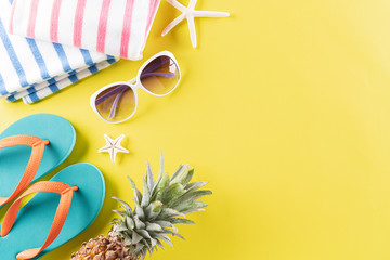 Colorful summer and holiday concept, Sunglasses, pineapple, flip flop, star fish and towel on yellow background.
